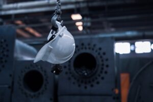 A technician inspects a metal railing while applying a protective industrial coating with spray equipment.